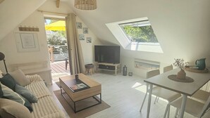 Un loft espacioso con techo alto, una zona de estar acogedora con sofá y mesa de centro, una mesa de comedor y un televisor en el centro.