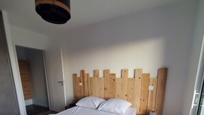 Ein modernes Schlafzimmer mit einem Bettgestell aus Holz, weißer Bettwäsche und einem Holz-Kopfteil.