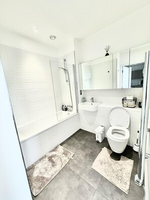 A modern bathroom with a bathtub, a sink, and a toilet. - Perfect Stay for Contractors & Families - Sleeps 7 (Bracknell)