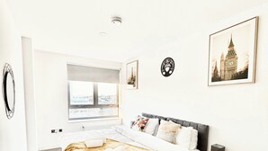 Ein modernes Schlafzimmer mit einem großen Bett, einem Nachttisch, einem Fenster und einer Wanduhr.