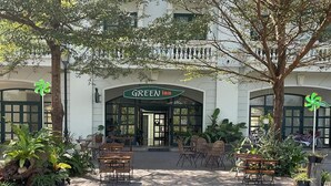 A hotel entrance with a sign reading "GREEN inn," outdoor seating with tables and chairs, and a well-maintained garden area.