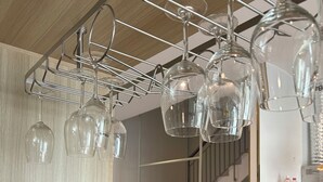 A modern interior with a staircase, wicker baskets, and hanging wine glasses.