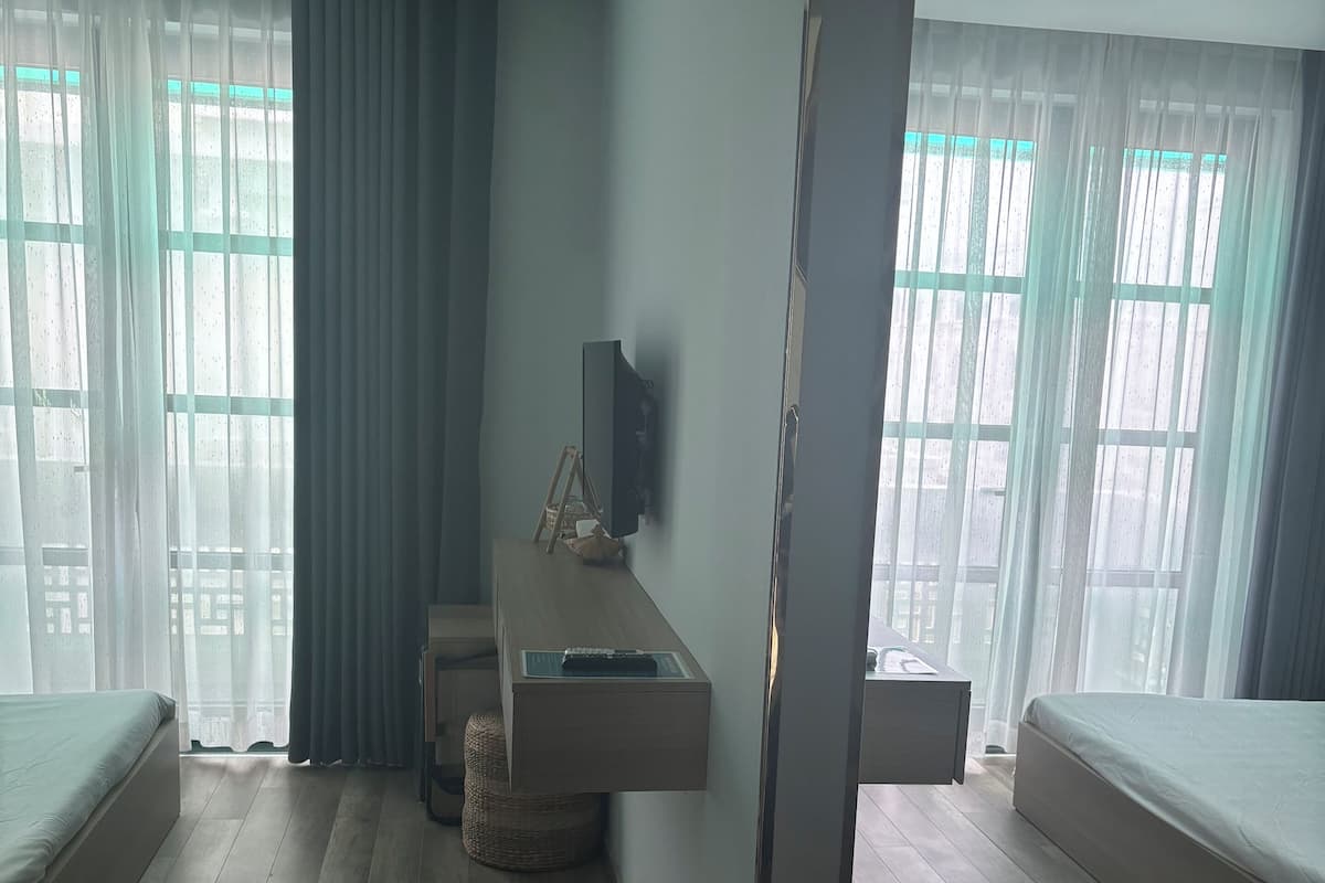 A modern hotel room with a large bed, a desk with a chair, and a television mounted on the wall.
