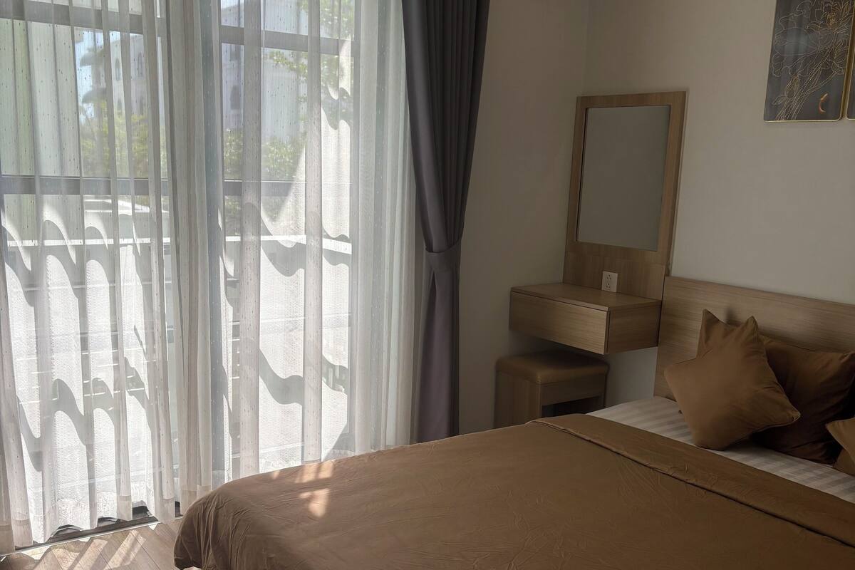 A bedroom with a large bed, a wooden headboard, a bedside table, and a mirror.