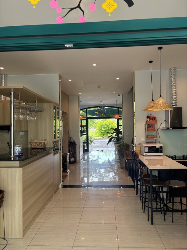 A modern kitchen with a central island, a dining area with chairs, and a view of the outdoors. - Green Inn Phu Quoc hotel (Phu Quoc)