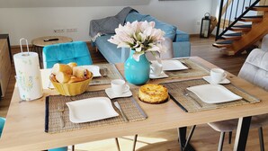 A dining table set with plates, cutlery, a basket of bread, a vase with flowers, and a cake. - The modern, newly renovated  90-square-meter apartment is waiting for you (Friedrichshafen)