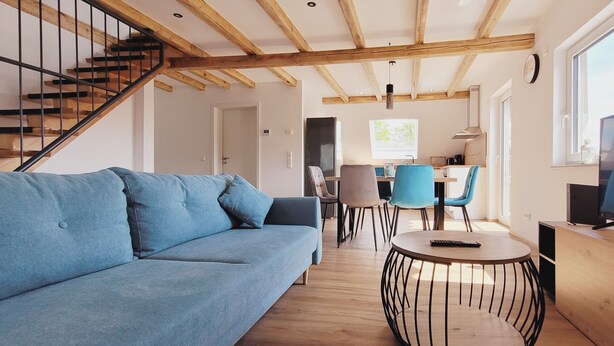 A modern living room with a blue sofa, a round coffee table, and a TV. - The modern, newly renovated  90-square-meter apartment is waiting for you (Friedrichshafen)