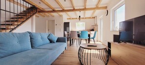 A modern living room with a blue sofa, a round coffee table, and a TV. - The modern, newly renovated  90-square-meter apartment is waiting for you (Friedrichshafen)