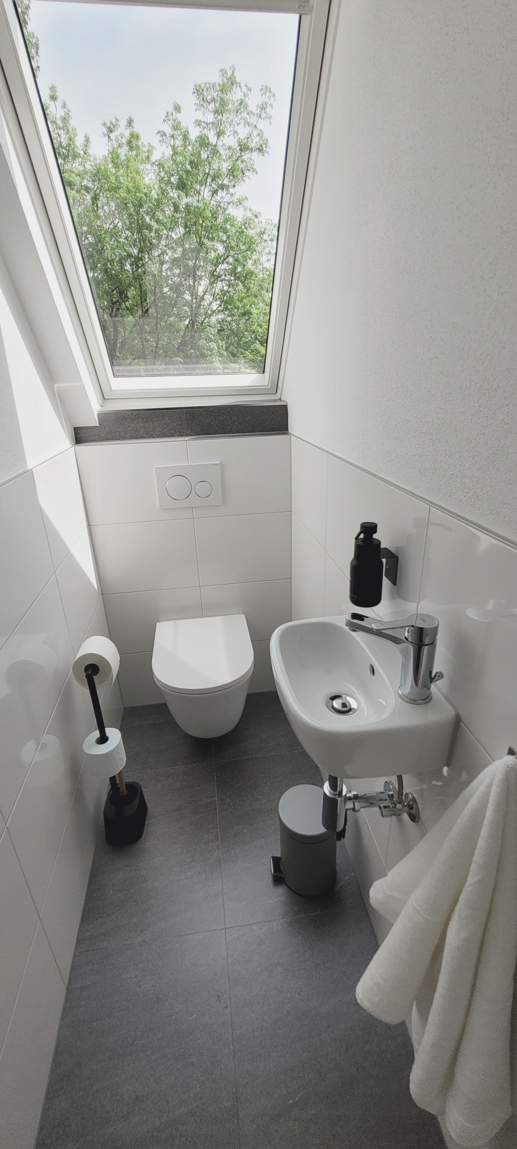 Pieni kylpyhuone, jossa on wc, pesuallas ja ikkuna.