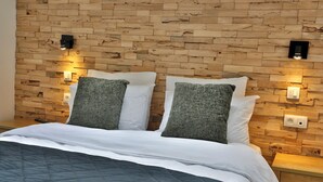 A bedroom with a wooden headboard, two bedside tables, and a bed with a quilted cover. - Hôtel L'ermitage (Houffalize)