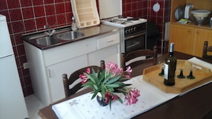 Una cocina con un lavabo, estufa y armarios. Hay un florero con flores en la encimera.