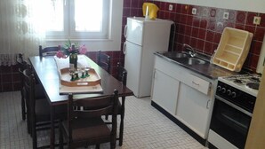 Una cocina compacta con una mesa de comedor, sillas, un refrigerador, un fregadero y una estufa.
