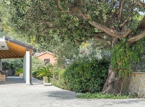 A covered outdoor area with a concrete pathway leading to a building with a sloped roof. - Vacation House Marija, Korčula (Korcula)