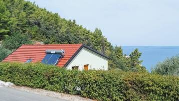 Una casa con techo rojo, paneles solares y vista al mar.