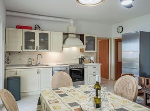 A compact kitchen with white cabinets, a Bosch oven, and a stainless steel refrigerator. - Vacation House Marija, Korčula (Korcula)