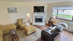 A living room with a fireplace, a television, and a large window. - Pismo Shores Paradise #111 - beach access - Pet Ok (Pismo Beach)