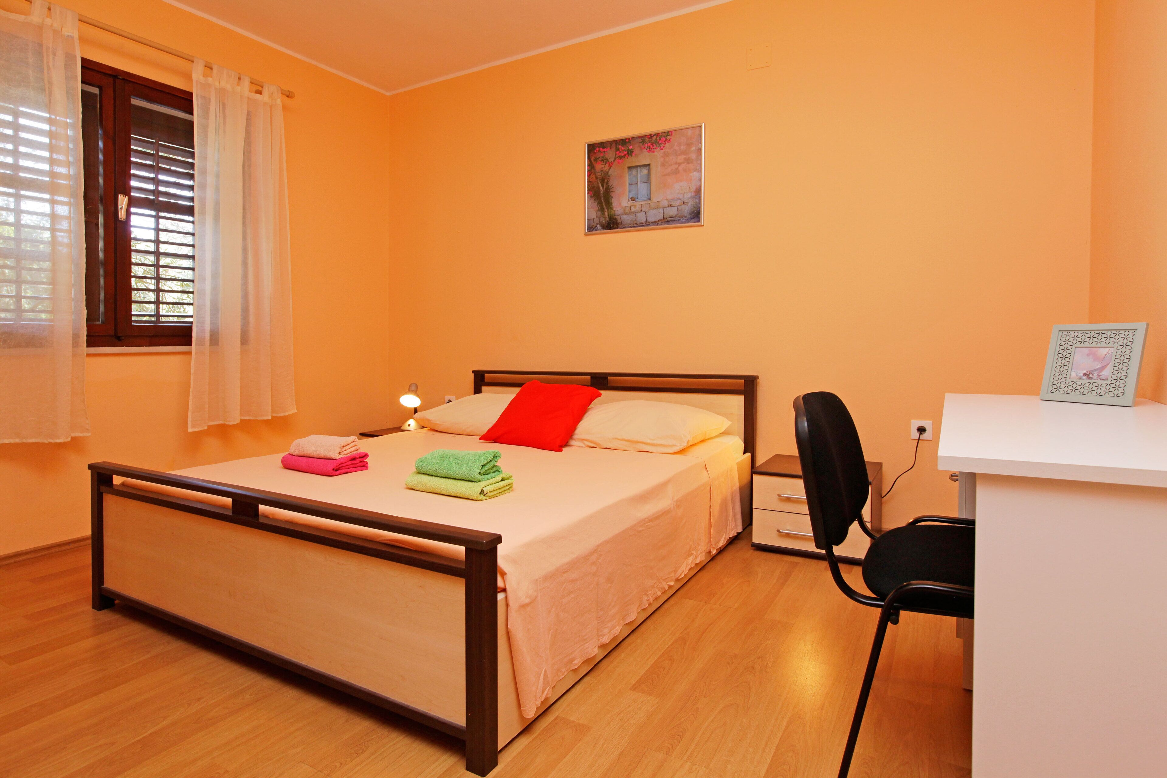 Een slaapkamer met een bed, een bureau en een stoel.