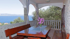 Une table en bois avec des bancs, sur un balcon donnant sur une étendue d’eau.