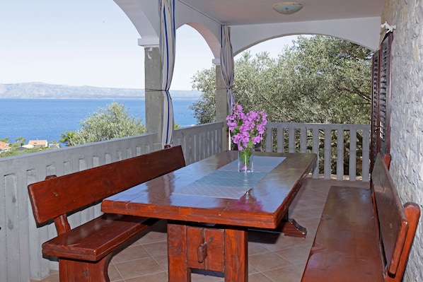 A wooden table with benches on a balcony overlooking a body of water.