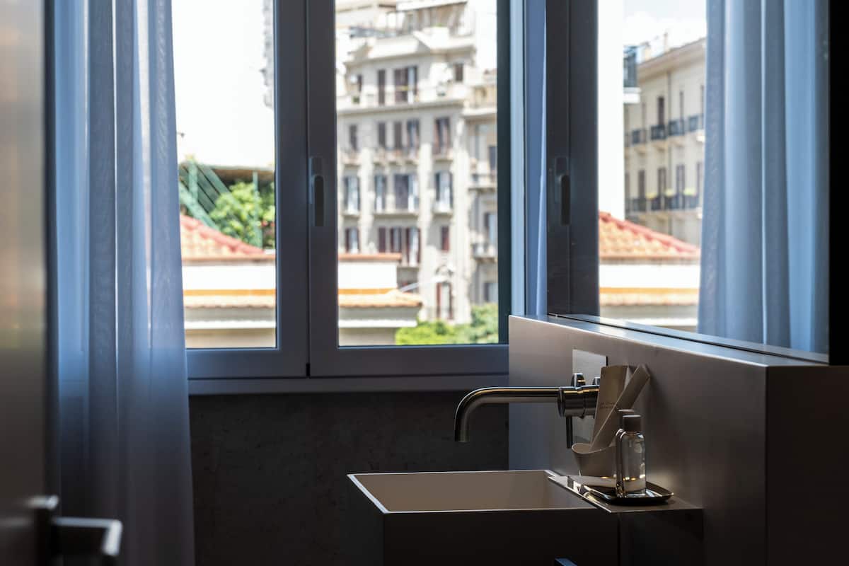 Un baño moderno con un ventanal grande, un lavamanos y un perchero para toallas.