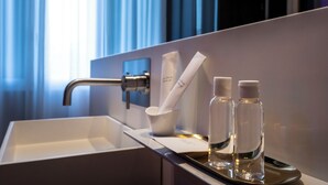 A modern bathroom with a sink, faucet, and two bottles of water on a tray. - Amorgiù Luxury Room (Palermo)