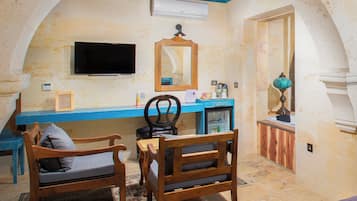 A room with a wooden desk, two chairs, a television, a mirror, and a small refrigerator.