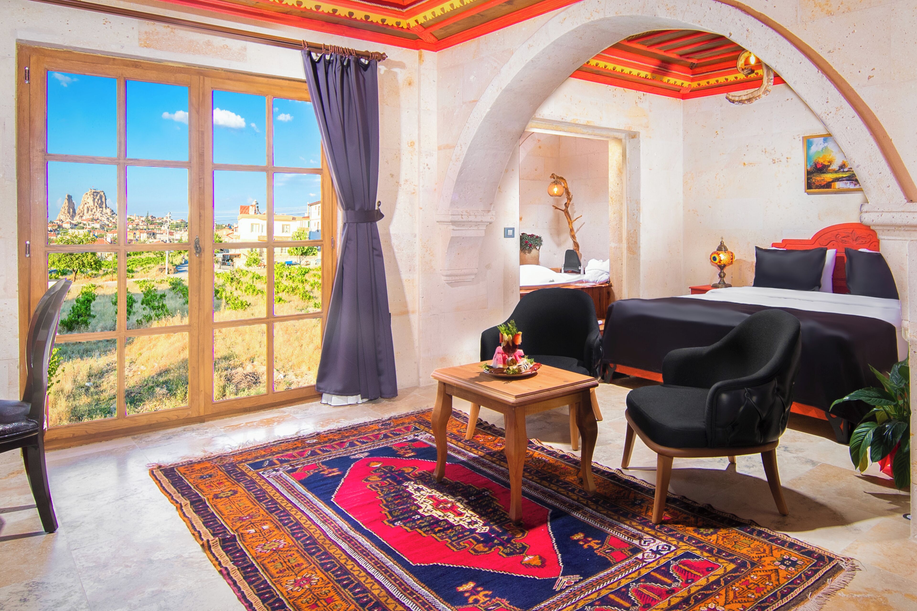 Une pièce avec une grande fenêtre, un lit, une chaise, une petite table et un tapis.