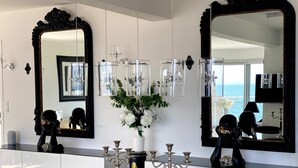 A modern interior with a glass dining table, white cabinets, and large mirrors.