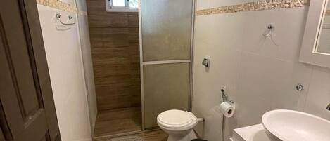 A compact bathroom with a toilet, sink, and shower area.
