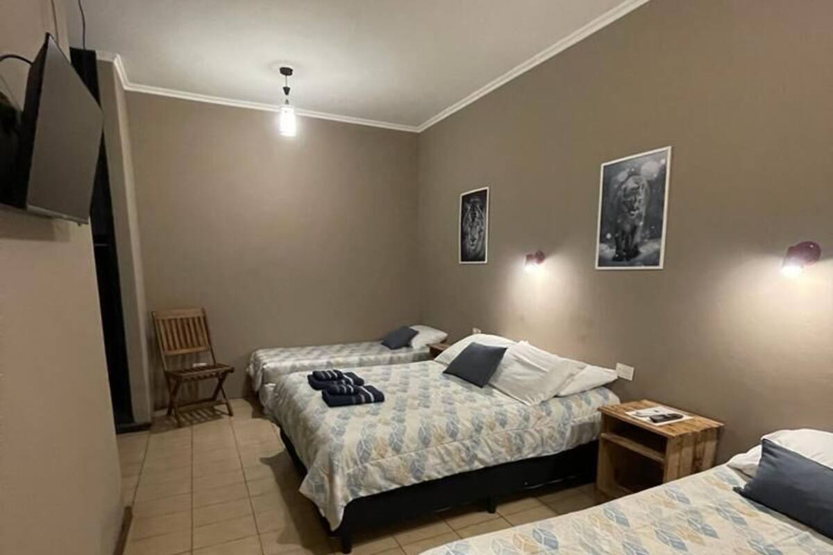 A bedroom with two beds, a chair, and a small table.