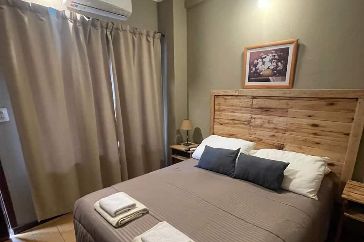 A neatly made bed with a wooden headboard, a bedside lamp, and a framed picture on the wall.