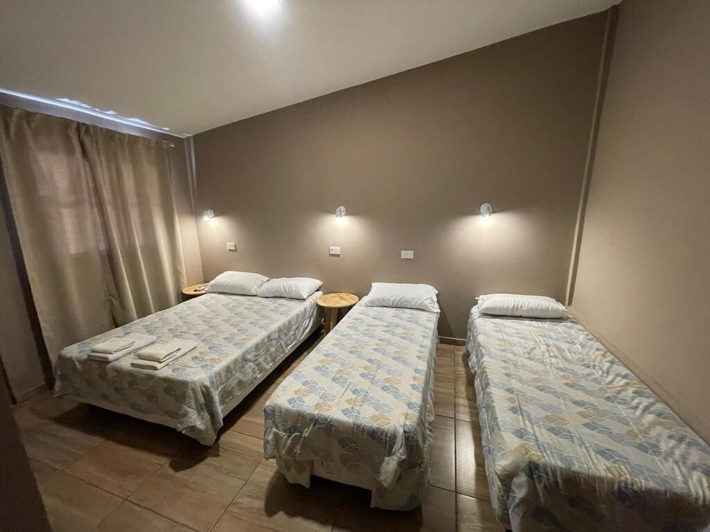 A room with two single beds, a small round table, and a wall-mounted light fixture.