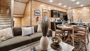 A cozy cabin interior with a wooden interior, a sofa, a dining table, and a kitchen area. - Near Dollywood | Hot Tub, Game Room & Home Theater (Sevierville)