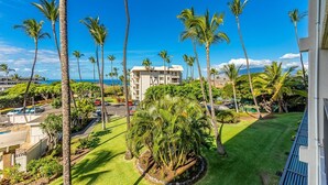 A residential area with palm trees, a building, and a clear blue sky.