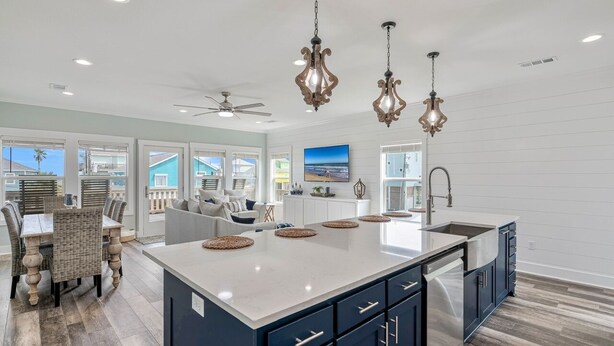 A spacious kitchen with a large island, dark cabinetry, and pendant lighting.