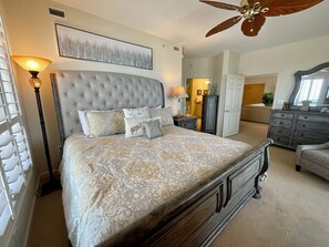 Ein Schlafzimmer mit einem großen Bett, einem Deckenventilator, einem Schminktisch und einem Nachttisch.