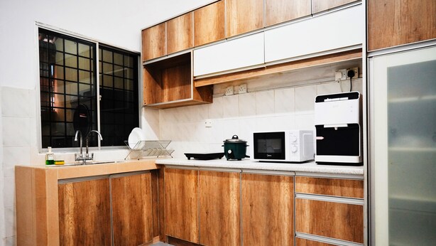 A modern kitchen with wooden cabinets, a stainless steel refrigerator, a microwave, and a kettle. - Peach Homestay Bandar Tasik Puteri (Rawang)