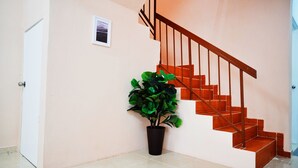 A staircase with wooden steps and metal railings, a potted plant, and a door on the left. - Peach Homestay Bandar Tasik Puteri (Rawang)