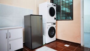 A compact laundry room with a washing machine and a refrigerator. - Peach Homestay Bandar Tasik Puteri (Rawang)