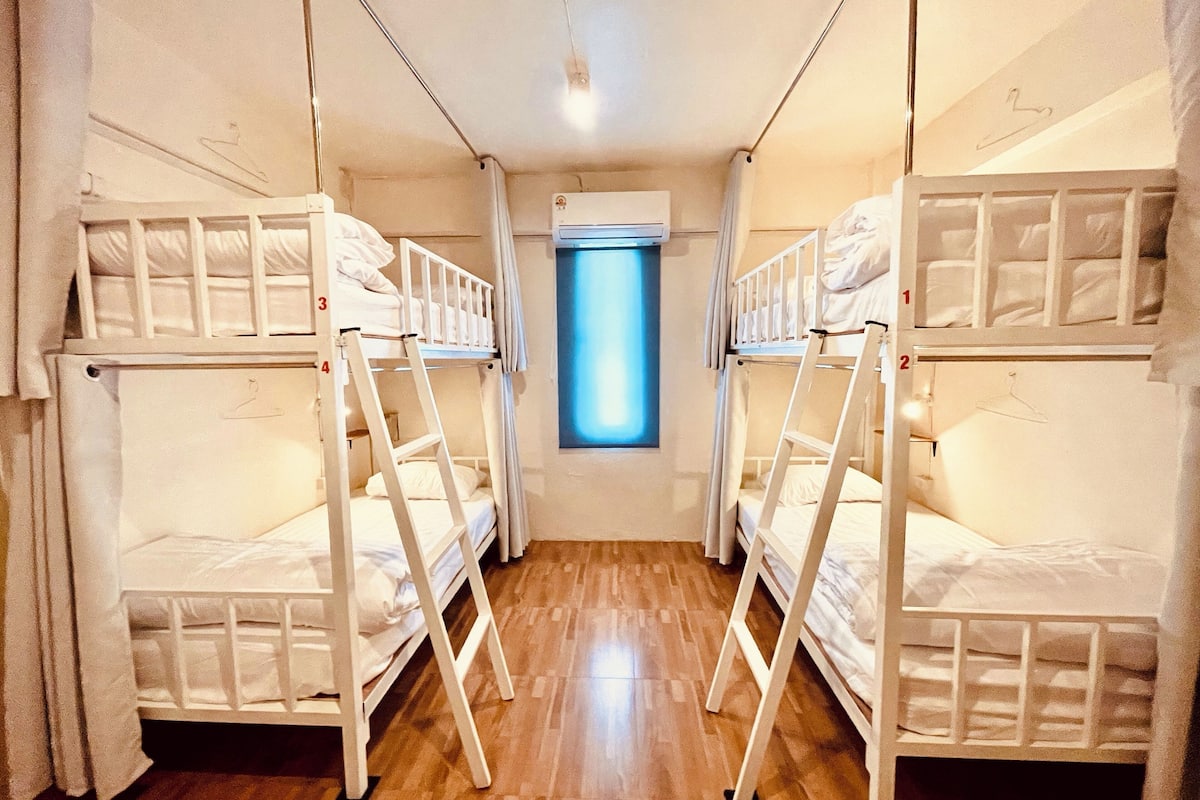 Un dormitorio con literas, una ventana y un equipo de aire acondicionado.