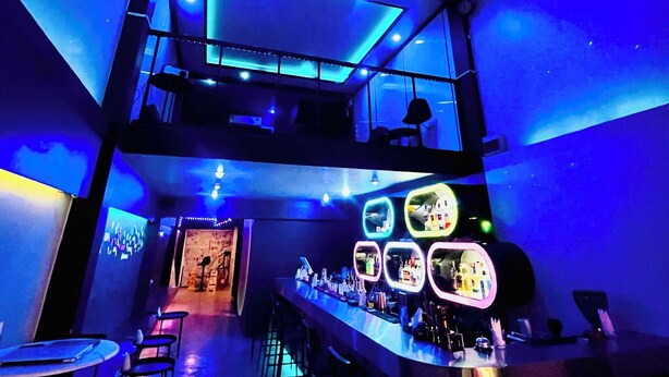 Un bar con techo temático de galaxia, varios niveles y diferentes opciones de asientos.