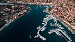 An aerial view of a coastal town with a marina filled with boats, surrounded by residential buildings and a hilly landscape. - Seaside Apartment Franica (Vela Luka)