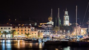 A marina at night with boats docked, a prominent clock tower, and buildings with warm lighting. - Seaside Apartment Franica (Vela Luka)