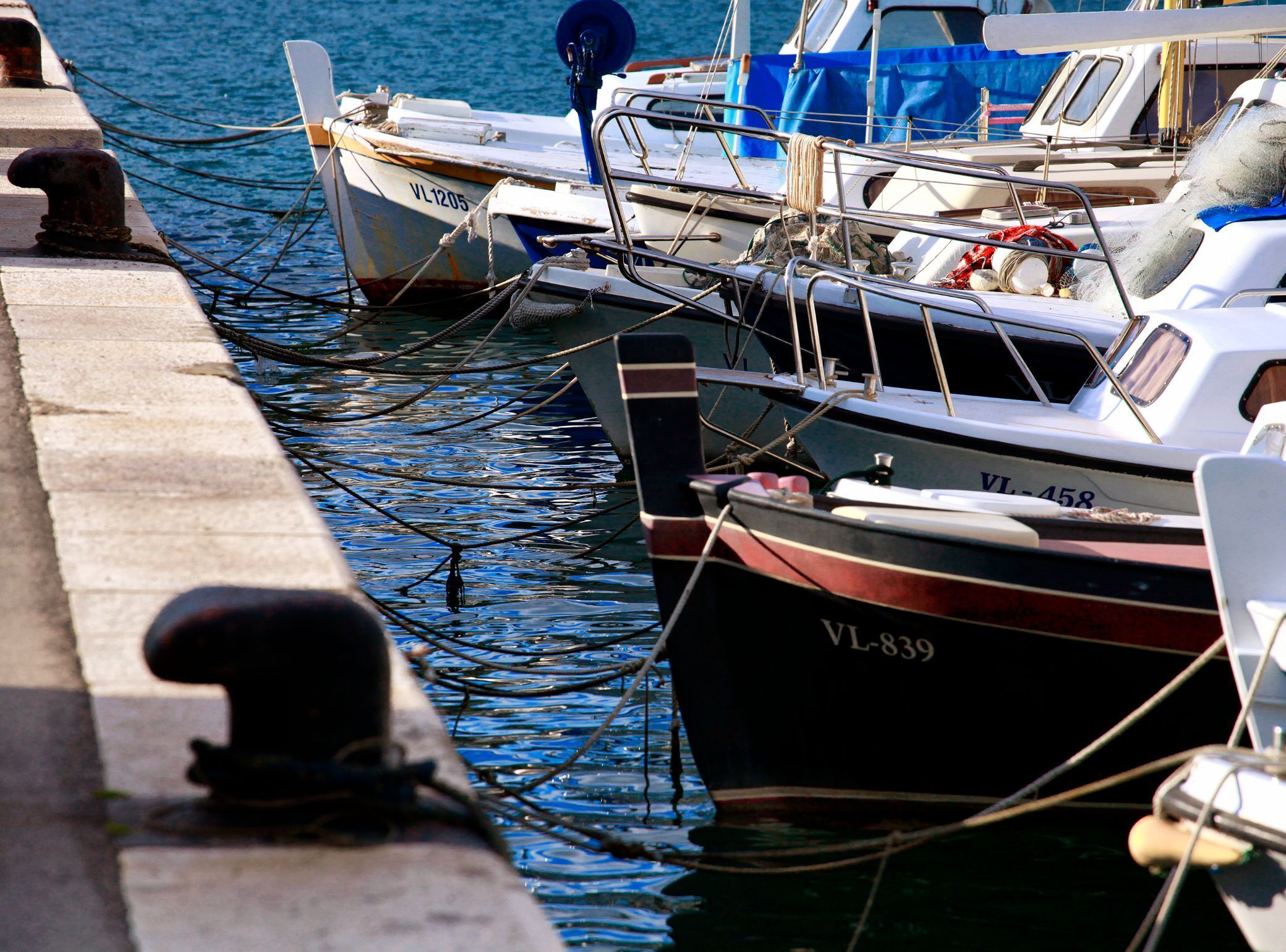 Vários barcos atracados em cais, com números de identificação visíveis.