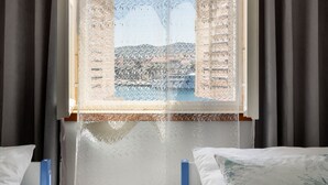 A room with a window covered by a net, a bed with white bedding, and a bedside table. - Seaside Apartment Franica (Vela Luka)