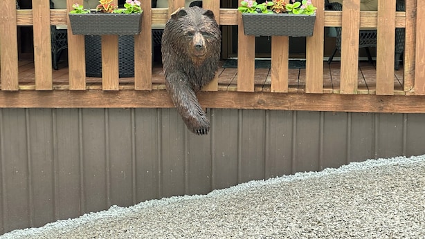 Una valla de madera con jardineras y una estatua de oso.