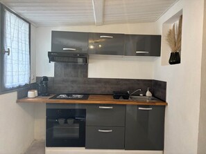 Een kleine keuken met een inbouwoven, een koffiezetapparaat en een spoelbak.