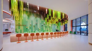 A modern lobby with a green wall, a bar area, and orange bar stools. - The Land of Legends Nickelodeon Hotels Antalya (Serik)