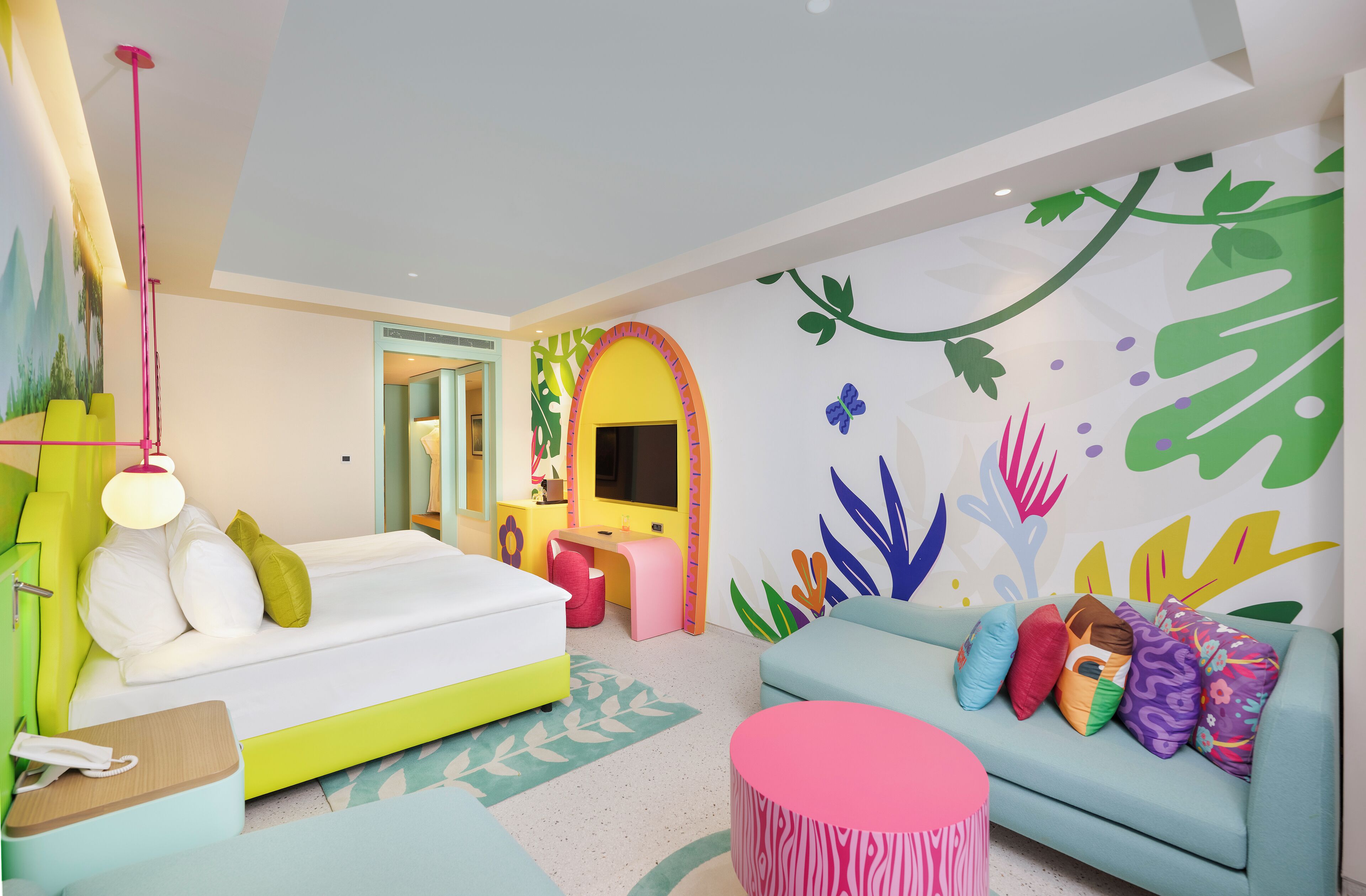 Une chambre aux couleurs vives, avec un lit, un canapé, un bureau et un miroir.