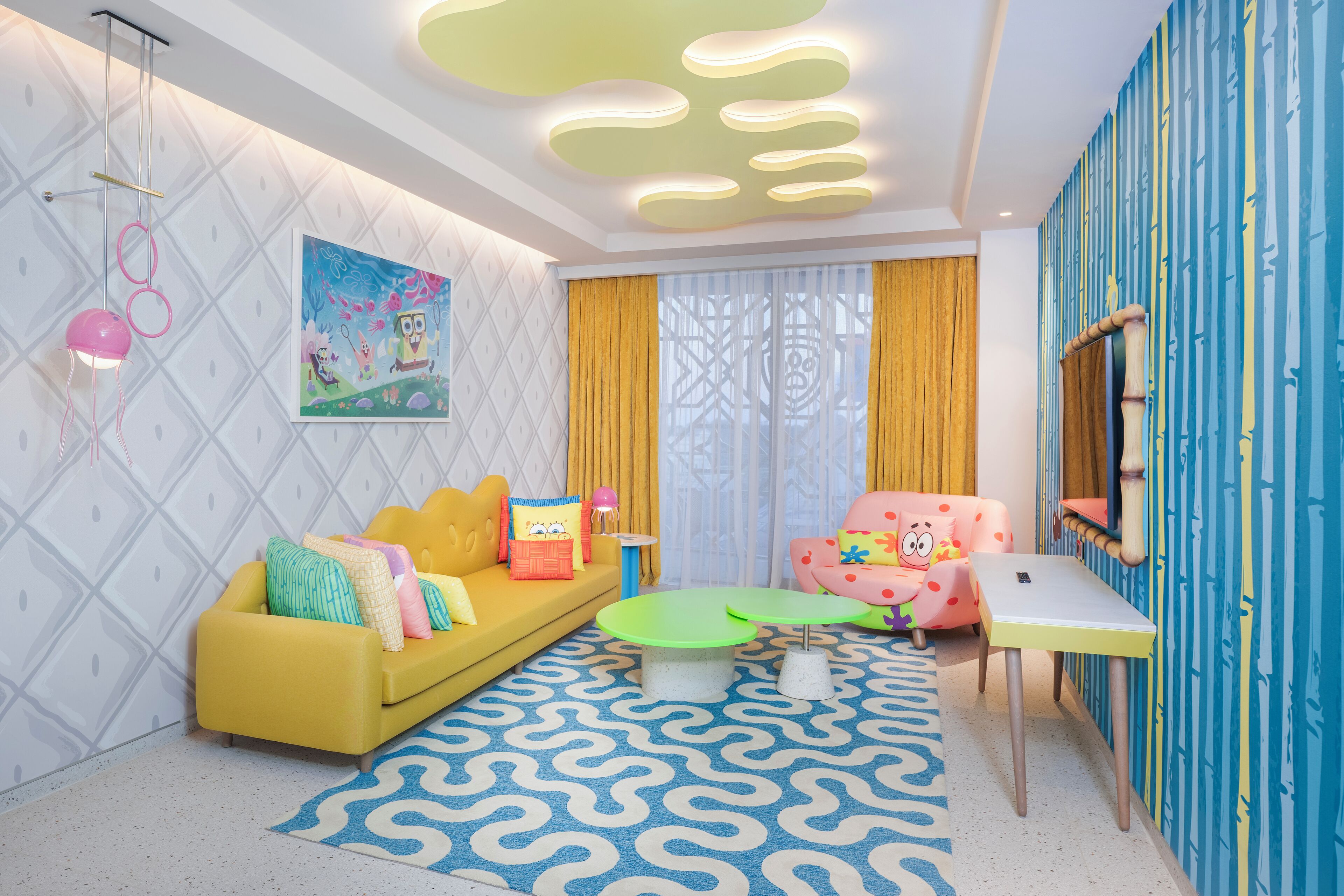 A vibrant living room with a yellow sofa, green coffee table, and a pink chair.